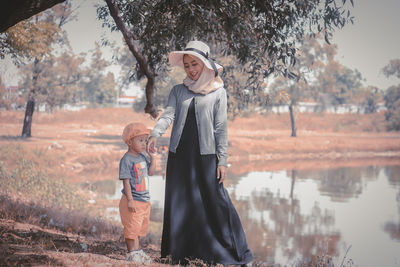 Portrait of young woman standing against lake