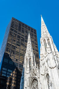 Low angle view of historic church in city against clear blue sky