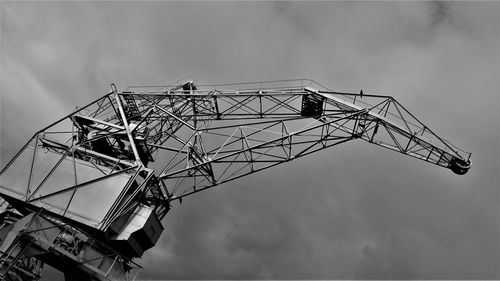 Low angle view of crane at construction site against sky