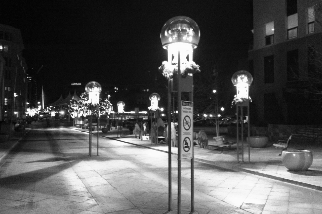 illuminated, night, street light, lighting equipment, built structure, architecture, building exterior, city, electric light, street, lamp post, empty, the way forward, incidental people, clear sky, outdoors, road, sidewalk, footpath, sky