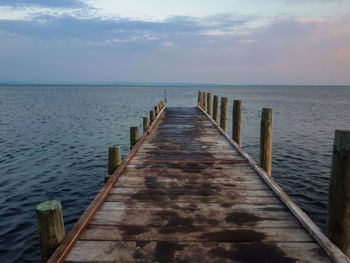 Wooden pier over sea against sky