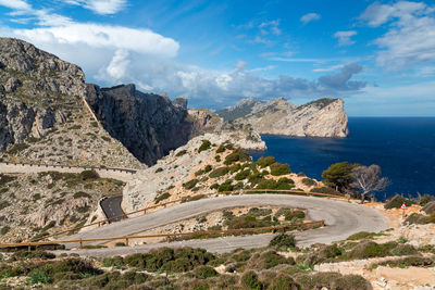 Scenic view of sea by mountain against sky