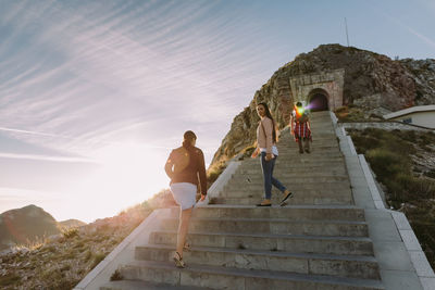 People on steps by mountain against sky
