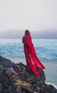 Tourist with red waving cape on rock scenic photography