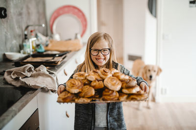 Smiling girl holding tray with cinnamon buns