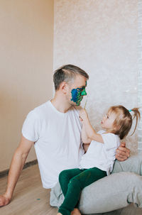 Mother and daughter against wall at home