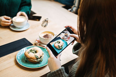 Rear view of woman using mobile phone on table