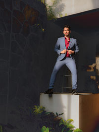 Young man looking away while sitting against wall