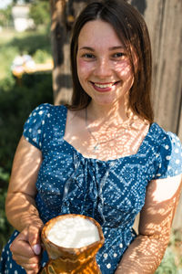 Young cute ukrainian girl holding jug of milk in countryside