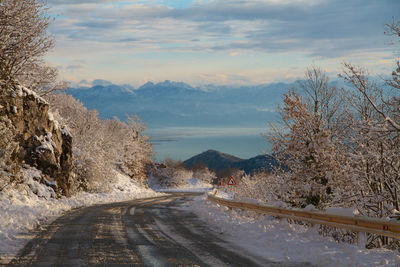 Road amidst snow covered mountains against sky