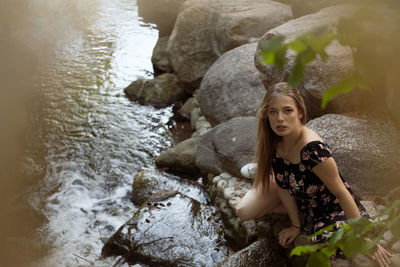 Portrait of young woman sitting on rock