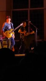 Woman holding guitar in dark room