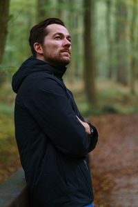Portrait of young man looking away in forest