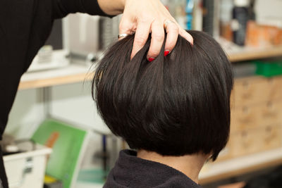Midsection of hairdresser with hand in woman hair at salon