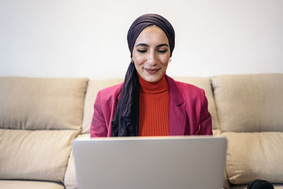 Portrait of young woman using laptop at home