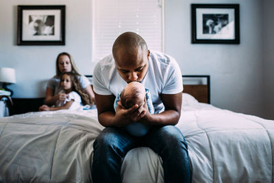 Center portrait of dad kissing newborn baby on bed