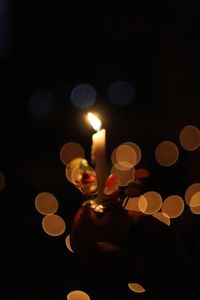 Lit candle against defocused lights in darkroom