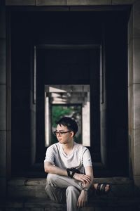 Young man looking away while sitting on staircase