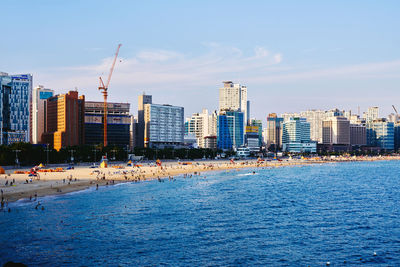 Sea by cityscape against sky