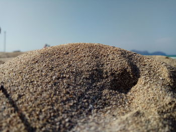 Close-up of rock on sand against sky