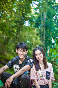 Portrait of smiling young couple against trees