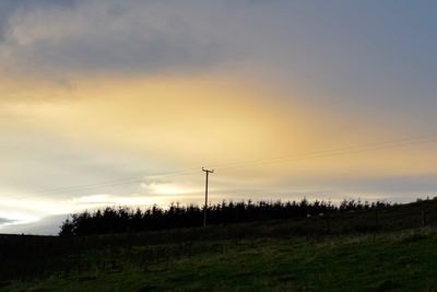 Silhouette electricity pylon against sky at sunset