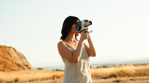 Pretty girl with vintage 8mm camera in the countryside