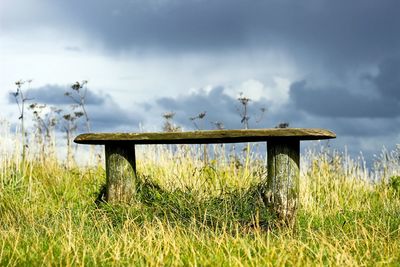 View of field against cloudy sky