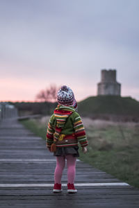 Rear view of woman with umbrella walking against sky