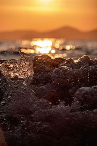 Close-up of rocks at beach against sky during sunset