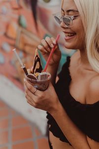 Close-up of smiling woman eating ice cream outdoors