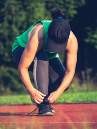 Young fit girl runner tying shoelaces. athletic woman on red running stadium track