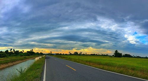 Road amidst field against sky