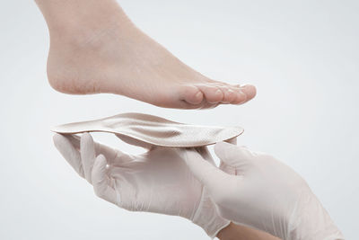 Cropped hand of woman feet over footwear