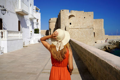 Beautiful young woman walking towards monopoli castle in apulia, italy