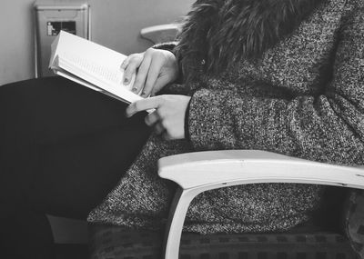 Midsection of woman reading book at home