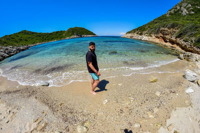 Full length of man on beach against blue sky