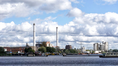 City at waterfront against cloudy sky