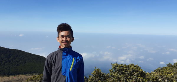 Portrait of young man standing against sky