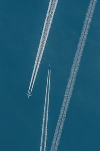 Low angle view of airplanes flying against blue sky