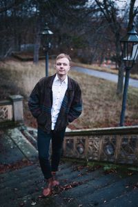 Portrait of young man standing against trees