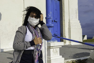 Mature woman protects herself from the wind in front of a church wearing mascara