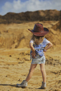 Rear view of woman standing on sand at beach
