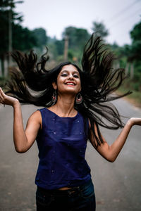 Young woman smiling while standing in the background