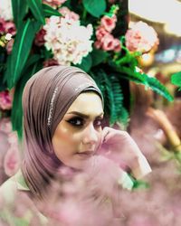 Close-up portrait of beautiful woman in hijab amidst flowers