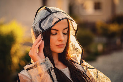 Young beautiful woman in hooded raincoat on rainy day