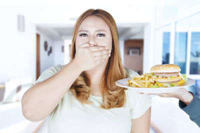 Cropped hand giving burger to woman at home