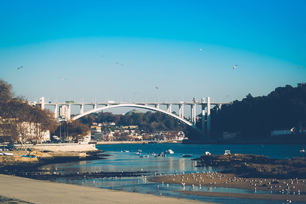 BRIDGE OVER RIVER AGAINST BLUE SKY IN CITY