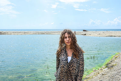 Young woman standing in sea against sky