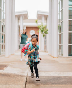 Young millennial mother sending daughter off back to school